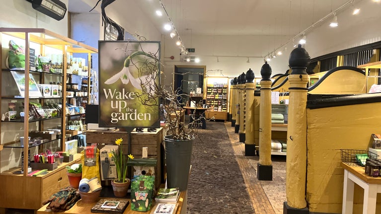 A view of the Stables Shop in spring with a 'Wake up the garden promotional board